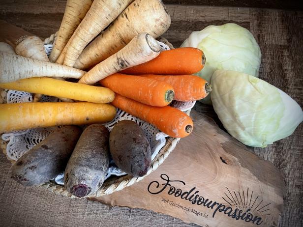 Verschiedene Gemüsesorten wie Karotten, Pastinaken, Rüben und Kohl liegen in einem Korb.