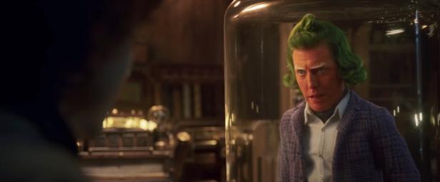Ein Mann mit grünen Haaren steht in einem Glasbehälter.
