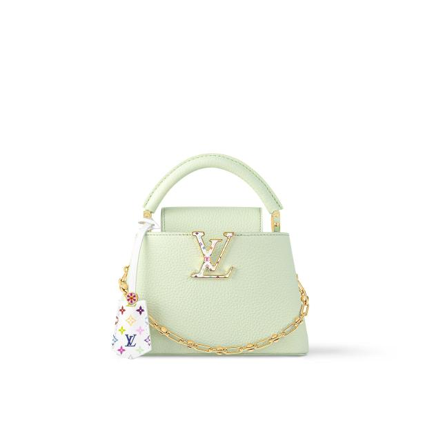 Eine hellgrüne Mini-Tasche mit goldenen Akzenten und einem bunten Anhänger.