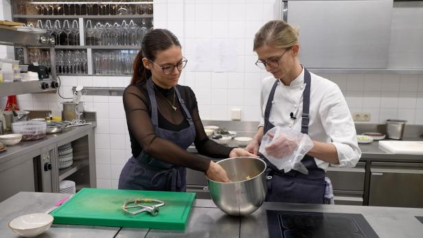 Zwei Köche bereiten Speisen in einer professionellen Küche zu.