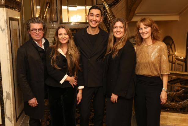 Fünf Personen posieren vor einer Treppe für ein Gruppenfoto.