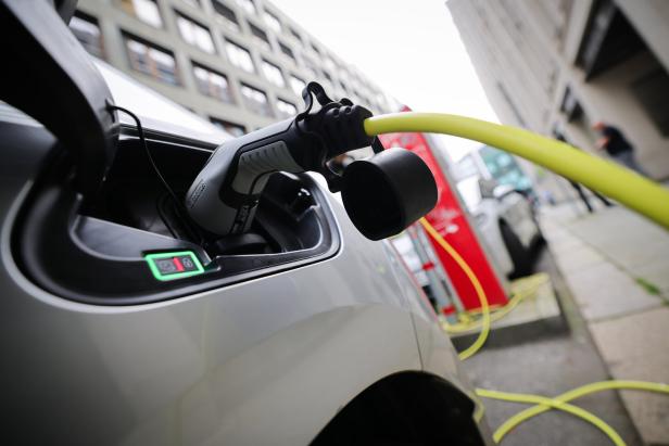Ein Elektroauto wird an einer Ladestation mit einem gelben Kabel aufgeladen.