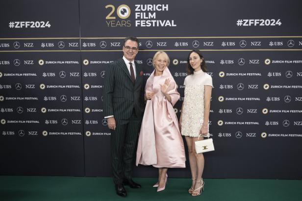 Drei Personen posieren vor einer Wand des Zurich Film Festivals 2024.