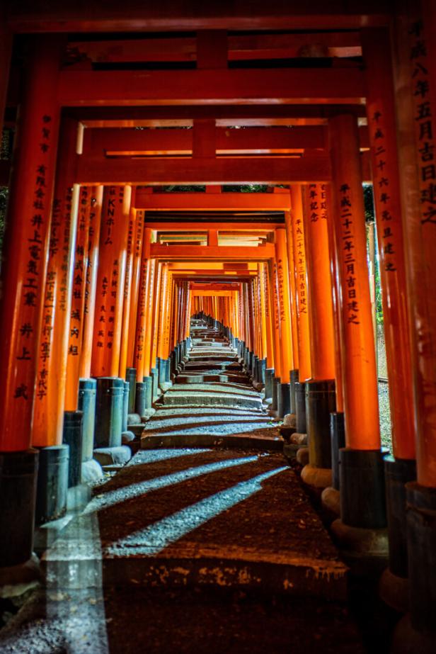 Ein Gang aus roten Torii-Toren führt zu einem Schrein in Fushimi Inari, Japan.
