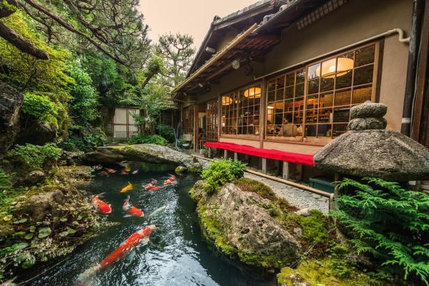 Karpfen schwimmen in einem Teich vor einem traditionellen japanischen Gebäude.