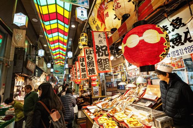 Ein belebter Marktstand in Japan mit vielen Laternen und Essensangeboten.