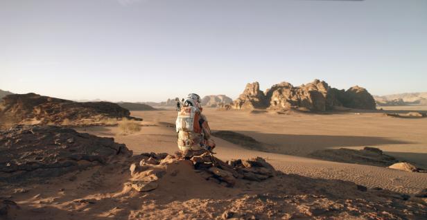 Szene aus dem Film „Der Marsianer“ mit Matt Damon – Er ist als Astronaut von hinten zu sehen. Vor ihm liegt die Wüste des Mars.