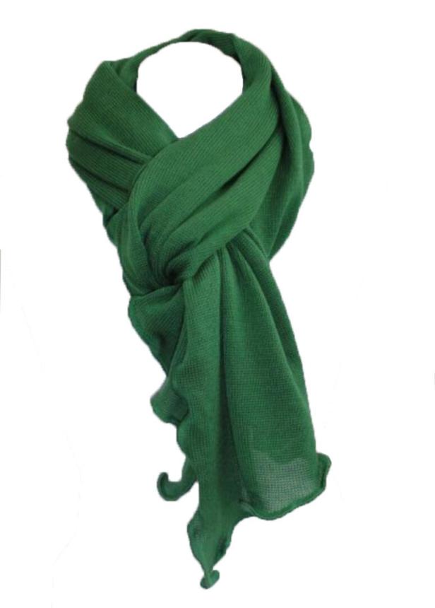 Ein grüner Strickschal ist kunstvoll drapiert.