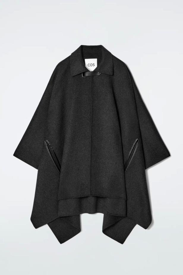 Ein grauer Wollcape-Mantel der Marke COS vor einem weißen Hintergrund.