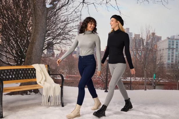 Zwei Frauen spazieren im Winter in Rollkragenpullovern durch einen Park.