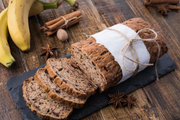 Bananenbrot mit Nüssen liegt auf einem dunklen Teller.