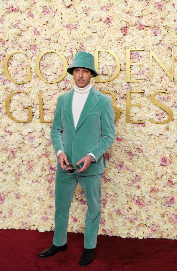 Jeremy Strong in einem mintgrünen Anzug und Hut vor einer Blumenwand der Golden Globes.
