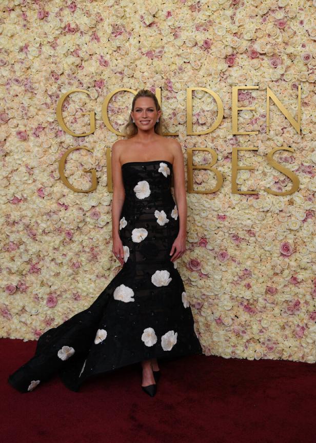Eine Frau in einem schwarzen, blumenverzierten Kleid vor einer Wand mit „Golden Globes“-Schriftzug.