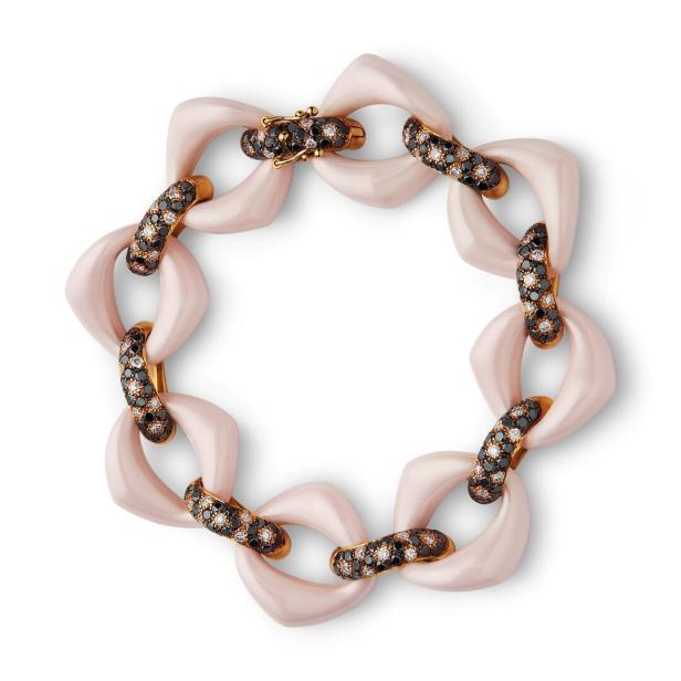Ein Armband mit rosafarbenen Gliedern und mit schwarzen und weißen Steinen besetzten Elementen.