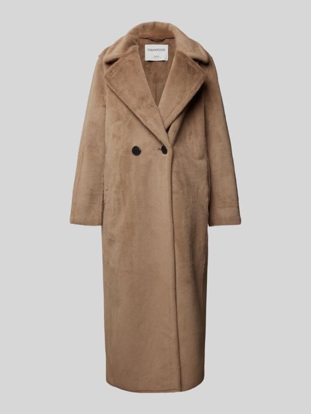 Ein langer, brauner Teddyfellmantel von Oakwood vor einem grauen Hintergrund.