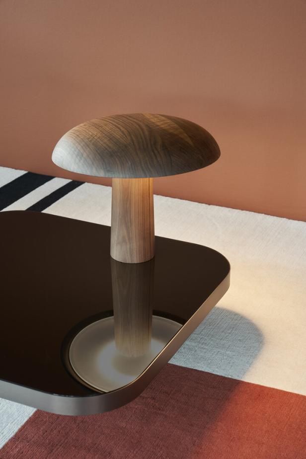 Eine hölzerne Pilzlampe steht auf einem dunklen Tisch.