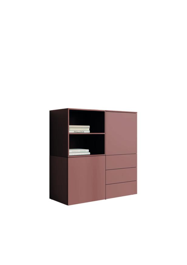 Ein rosafarbenes Sideboard mit offenen Regalen und Schubladen, auf den Regalen liegen Bücher.