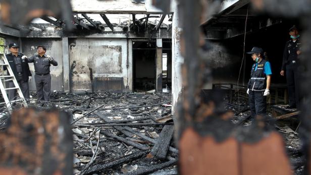 Forensic experts inspect a burnt building at the P