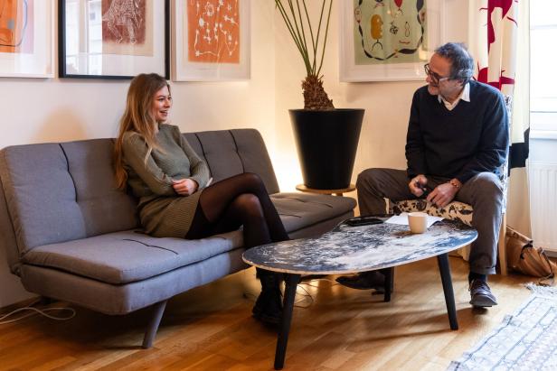 Zoë sitzt auf einem Sofa, während ein Mann ihr gegenübersitzt.