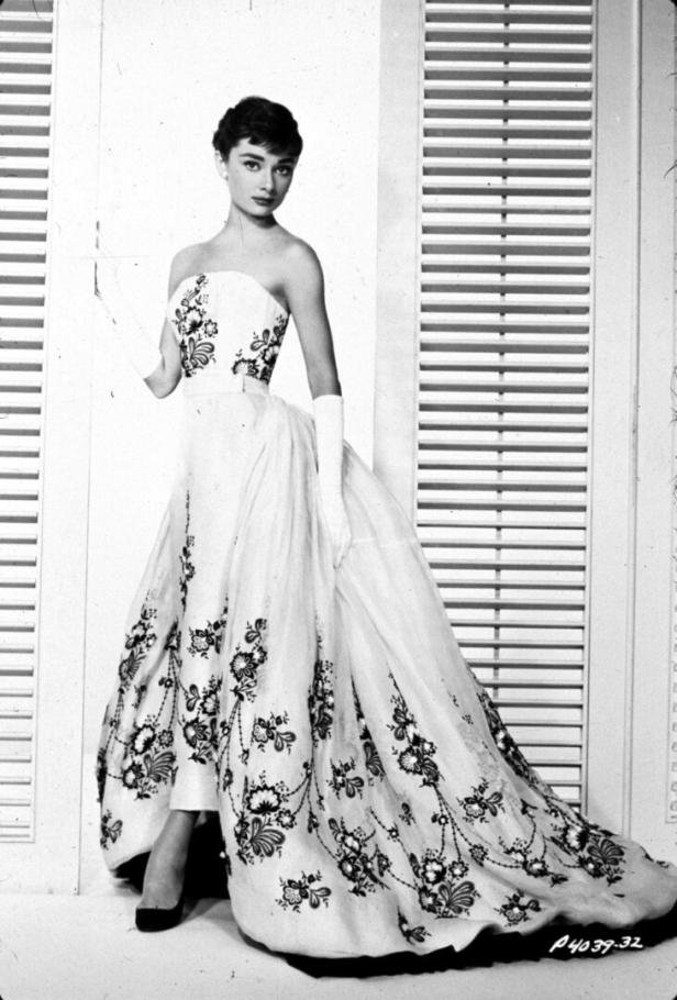 Audrey Hepburn in einem schulterfreien Kleid mit Blumenmuster und langen Handschuhen.