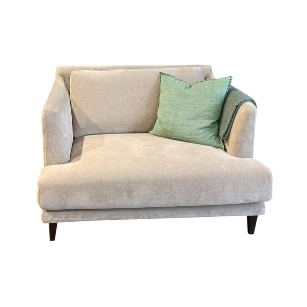 Ein beiges Sofa mit einem grünen Kissen und einer Decke darauf.