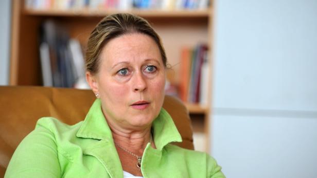 Eine Frau mit grünem Blazer sitzt in einem Sessel.