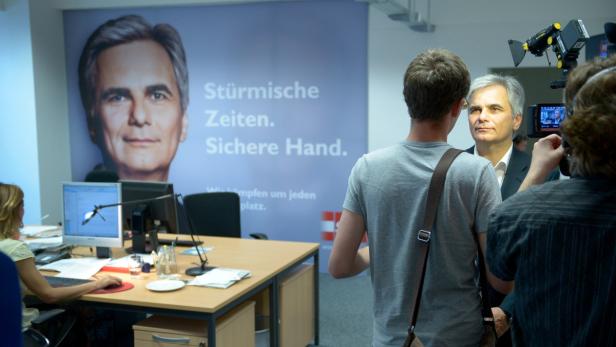 Ein Mann wird vor einem Wahlplakat interviewt.
