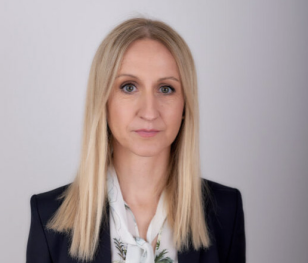 Porträt einer Frau mit blonden, schulterlangen Haaren und dunklem Blazer.