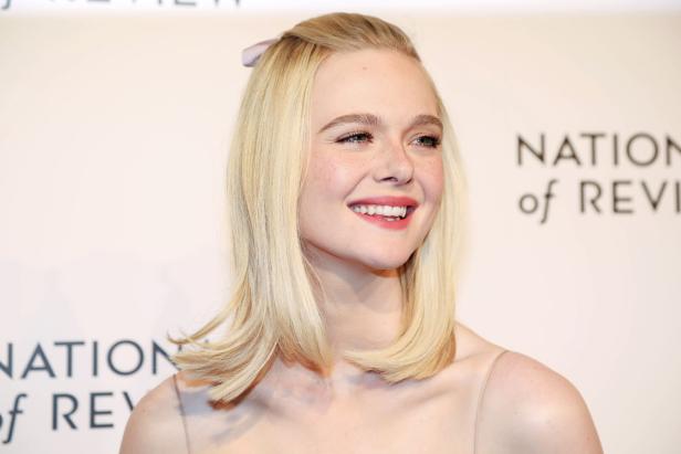 Elle Fanning lächelt mit blonden Haaren und einem hellrosa Lippenstift.