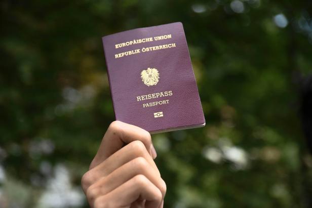 Eine Hand hält einen österreichischen Reisepass.