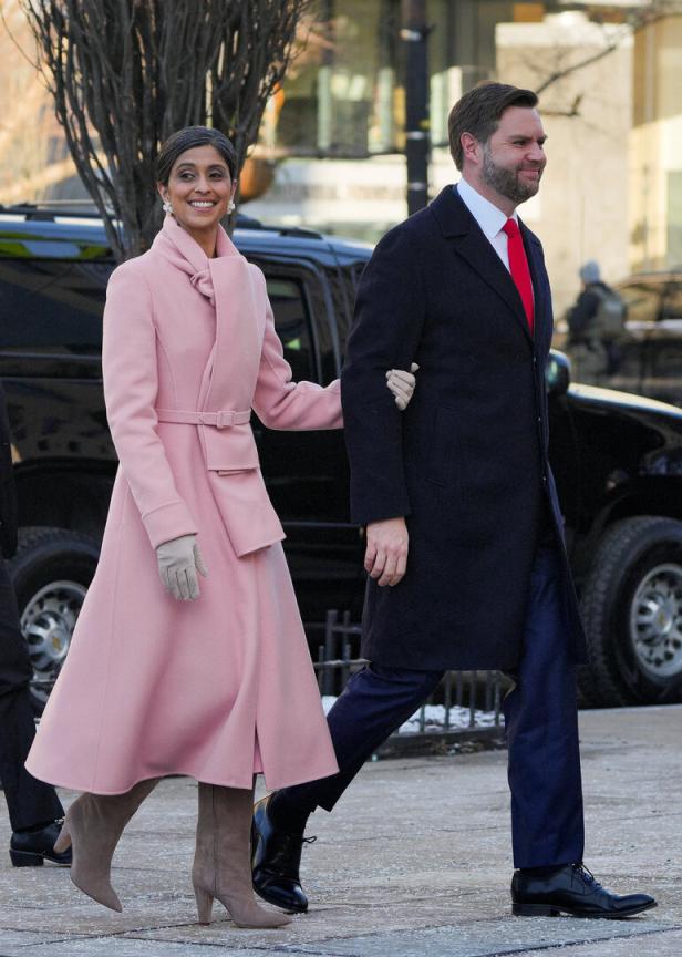 Eine Frau in einem rosa Mantel geht Arm in Arm mit einem Mann in einem dunklen Mantel.