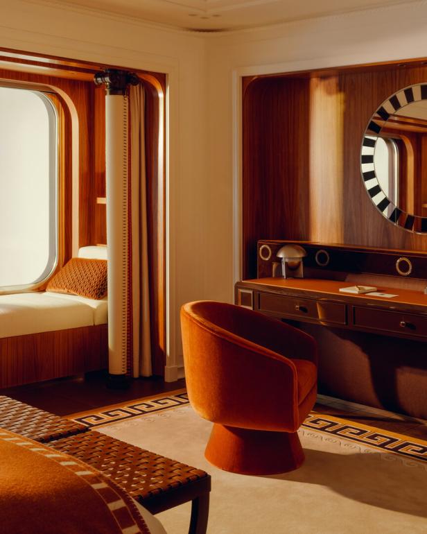 Ein luxuriöses Interieur mit einem Schreibtisch, einem Sessel und einem Fensterplatz in warmen Farbtönen.