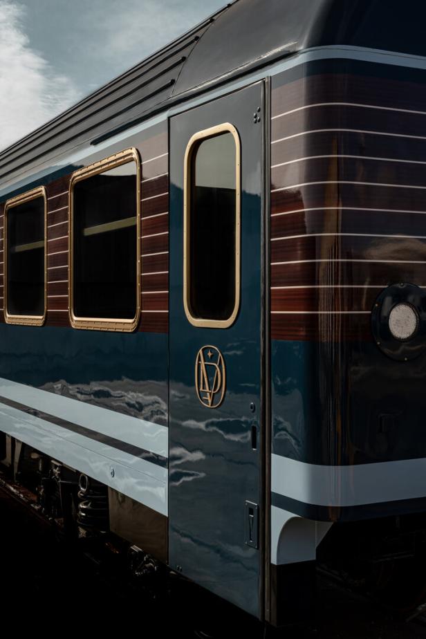 Detailansicht eines luxuriösen Zugwaggons mit blauer Lackierung und Holzelementen.