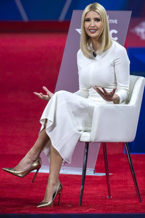 Ivanka Trump sitzt auf einem weißen Stuhl vor einem roten Hintergrund.