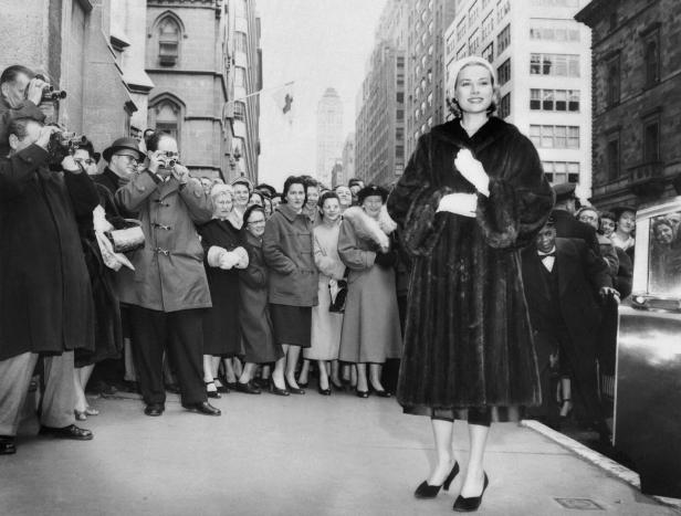 Grace Kelly in einem Pelzmantel wird von Fotografen und Zuschauern in New York empfangen.