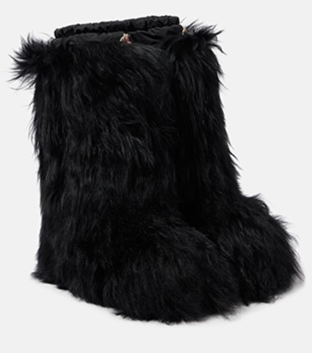 Ein Paar schwarze, fellartige Stiefel stehen vor einem weißen Hintergrund.