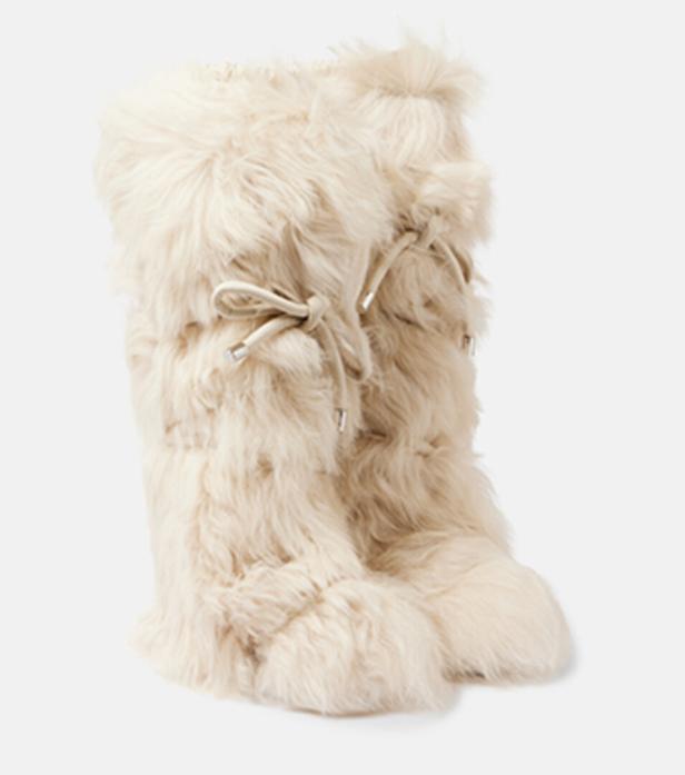 Ein Paar cremefarbene, kniehohe Fellstiefel mit Schnürung stehen vor einem weißen Hintergrund.
