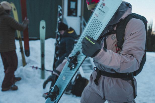 Ein Skifahrer trägt seine Ski der Marke Black Diamond über der Schulter.