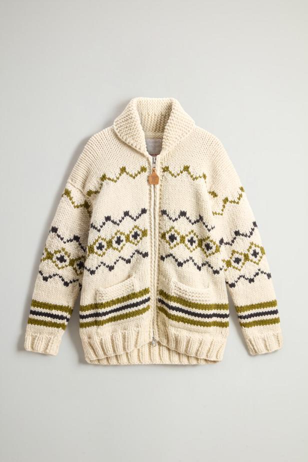 Eine cremefarbene Strickjacke mit Reißverschluss und geometrischen Mustern in Grün und Schwarz.