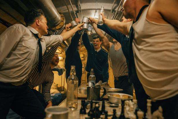 Eine Szene aus "Whiskey on the Rocks": Eine Gruppe von Männern in Matrosenkleidung stößt in einem Schiffsinneren mit Getränken an.