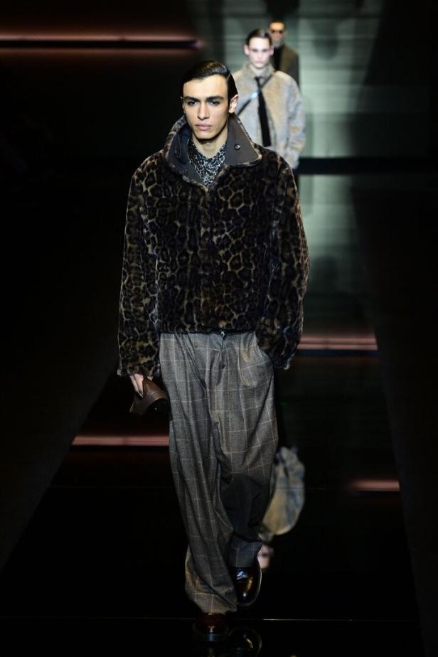 Ein Mann in einer Jacke mit Leopardenmuster und einer weiten Hose auf einem Laufsteg.