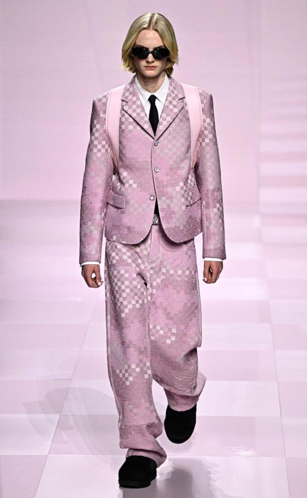 Ein Model in einem rosa Anzug mit Schachbrettmuster auf einem Laufsteg.