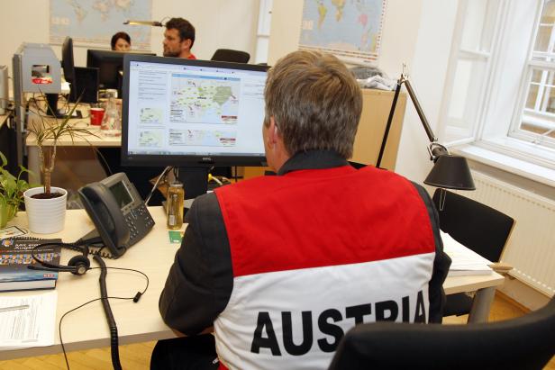 Ein Mann mit einer Jacke mit der Aufschrift „AUSTRIA“ sitzt vor einem Computerbildschirm.