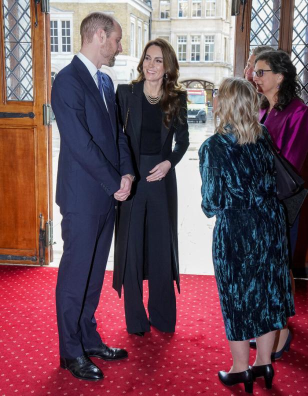 Prinz William und Prinzessin Kate unterhalten sich mit mehreren Personen in einem Gebäude.