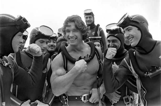 Arnold Schwarzenegger posiert mit anderen Tauchern für ein Foto.
