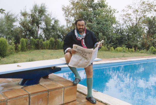 Luciano Pavarotti sitzt am Pool und liest Zeitung.