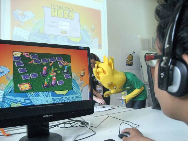 Eine Person im gelben Kostüm spielt ein Computerspiel namens „Internet Hero“.