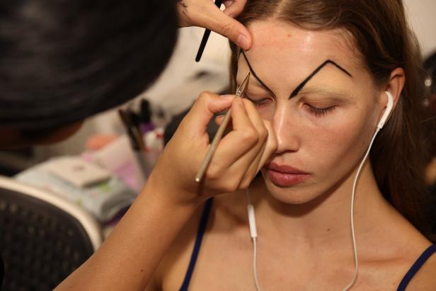 Eine Frau bekommt ein auffälliges, schwarzes Augen-Make-up aufgetragen.