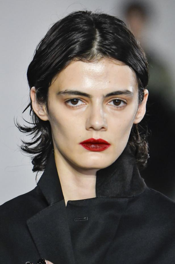 Nahaufnahme eines Models mit dunklem Haar und rotem Lippenstift.