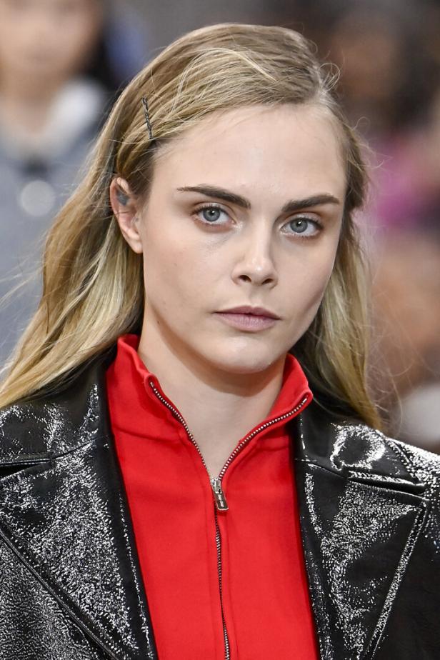 Cara Delevingne trägt eine rote Jacke und eine glänzende schwarze Jacke.